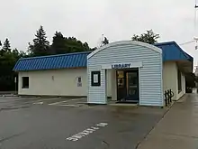 Maple Plain Library, a one-story white building with a blue sloped roof and a teal, arched entryway.