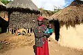 Marakwet woman holding her child in front of her house