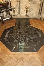 Black marble memorial set into the floor that reads: "In remembrance of all those who drowned when the motor vessel Marchioness was struck near Southwark Bridge on Sunday 20 August 1989. Many waters cannot quench love"