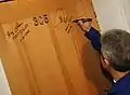 Pontes signing the Baikonur Cosmodrome checkout hotel room, an Astronaut/Cosmonaut tradition
