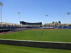 A baseball game being played on a green field surrouned by blue stadium seats