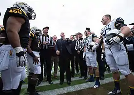 Man flips a cookie to determine which team will kick off.