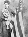 Mena E. Williams Hirshberg holding a US flag made from silk grown at The Grove, 1885
