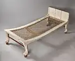White-painted bed red accents and strung mattress standing on leonine legs