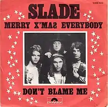 A monochrome photograph of Slade, with a white border, set almost centrally in a red square. The words "SLADE" dominate the cover, underneath which is written "MERRY X'MAS EVERYBODY". Underneath the photograph are the words "DONT BLAME ME". White stars border the left and right sides of the photograph.