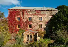 front of a three-story stone building partly covered in ivy