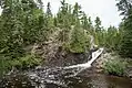 The Upper Falls of the Montreal River, showing the rugged shoreline and predominantly coniferous forest