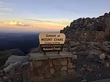 The United States Forest Service sign at the summit of Mount Evans with the following inscription: ""Summit of Mount Evans Elevation 14,130 feet Arapaho & Roosevelt National Forests."