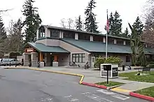 A building with a triangular, green roof and several windows.