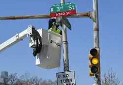 City worker installing a “N3RD St” sign at the intersection with Spring Garden Street