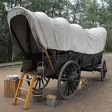 Narrow covered wagon of the type settlers used to goods and people west from Ontario via Winnipeg to Alberta, c. 1885