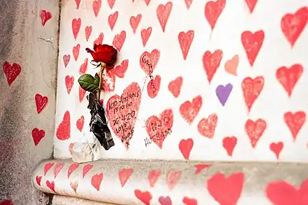 A red rose stuck to the wall with its stem within a small bag filled with water