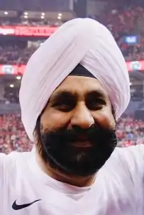 Portrait photograph of Bhatia wearing white at a Toronto Raptors basketball game in 2019