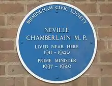 Round blue plaque on a brick wall. It says "BIRMINGHAM CIVIC SOCIETY", "NEVILLE CHAMBERLAIN M.P.", "LIVED NEAR HERE 1911–1940", "PRIME MINISTER 1937–1940".