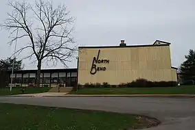 A yellow wooden lodge building with a leafless tree in front.