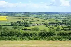 The roofs of a row of houses amongst green fields.