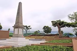 A photograph taken in 2014 of a large memorial within a school surrounded by trees.