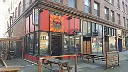 Street view of the red storefront bar, with picnic tables in front