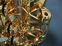 The lower portion of a P. Mauriat alto saxophone, showing the mother of pearl key touches and engraved brass pad cups