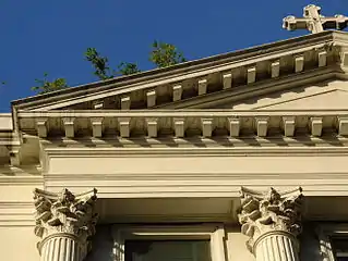 A close-up of the left corner of the pediment of the facade