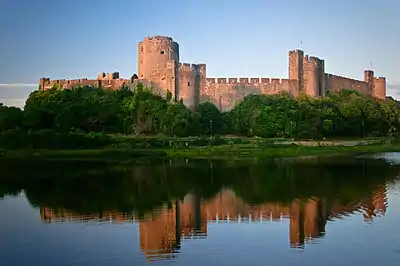 exterior of a large medieval castle with water in foreground