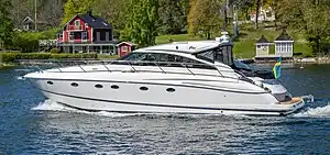 In the foreground, a large, white motor yacht on the sea, with an island in the background.