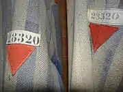 Red emblems of a political enemy on a Dachau detainee's clothing..mw-parser-output .citation{word-wrap:break-word}.mw-parser-output .citation:target{background-color:rgba(0,127,255,0.133)}^