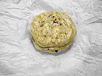 Pupusas for carryout, in El Salvador, are wrapped in plastic and then in paper. (Here the paper is unwrapped to show the pupusas)