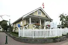 the Thrall residence, a yellow house with a white picket fence.