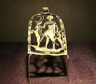 Gold pendant with a figure of a child standing on a crocodile grasping snakes and gazelles