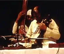 Narayan and another man perform on a platform.