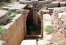 A corridor built of ashlars leads to a ruined archway