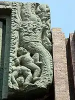 Top-left corner of the scroll round the entrance; the lower boy shows the viewer his bottom