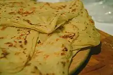 Thin layers of bread with browning on surface.