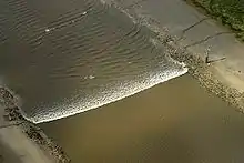 A tidal bore wave moves along the River Ribble between the entrances to the Rivers Douglas and Preston.