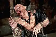 A behind-the-scenes photograph of actor Paul McCrane in a prosthetic costume depicting melting skin