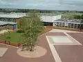 View from main block of Quad with Sports hall, Sixth Form Centre and Humanities blocks with sports fields behind.