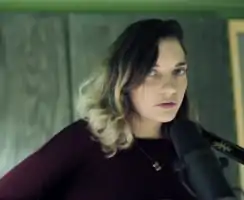 Tucker in a dark red shirt singing into a microphone