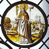 Renaissance roundel using only black or brown glass paint, and silver stain. The bishop-saint Lambrecht of Maastricht stands in an extensive landscape, 1510–20. Diameter .mw-parser-output .frac{white-space:nowrap}.mw-parser-output .frac .num,.mw-parser-output .frac .den{font-size:80%;line-height:0;vertical-align:super}.mw-parser-output .frac .den{vertical-align:sub}.mw-parser-output .sr-only{border:0;clip:rect(0,0,0,0);clip-path:polygon(0px 0px,0px 0px,0px 0px);height:1px;margin:-1px;overflow:hidden;padding:0;position:absolute;width:1px}8+3⁄4&nbsp;in (22&nbsp;cm). Designed to be placed low, close to the viewer.