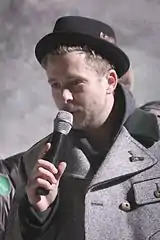 A color photograph of American musician Ryan Tedder performing live into a microphone.