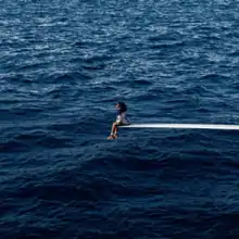 Cover art for "SOS": SZA sitting at the edge of a diving board in the middle of the sea