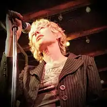 Timms at a microphone, photographed from below