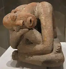 Terracotta seated figure; 13th century; earthenware; 29.9&nbsp;cm (11.mw-parser-output .frac{white-space:nowrap}.mw-parser-output .frac .num,.mw-parser-output .frac .den{font-size:80%;line-height:0;vertical-align:super}.mw-parser-output .frac .den{vertical-align:sub}.mw-parser-output .sr-only{border:0;clip:rect(0,0,0,0);clip-path:polygon(0px 0px,0px 0px,0px 0px);height:1px;margin:-1px;overflow:hidden;padding:0;position:absolute;width:1px}3⁄4&nbsp;in.) high; Metropolitan Museum of Art (New York City, USA) The raised marks and indentations on the back of this hunched Djenné figure may represent disease or, more likely, sacrification patterns. The facial expression and pose could depict an individual in mouring or in pain