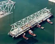 Main bridge span secure on barge being towed away