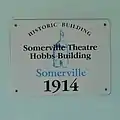 The historical marker sign on the face of the Somerville Theatre Hobbs Building