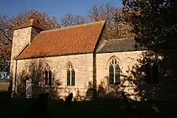 A small stone church seen from the southeast; at the far end is a short tower with a hipped roof