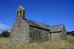 A simple stone church with a slate roof, a bellcote on the nearest gable and a transept on the right