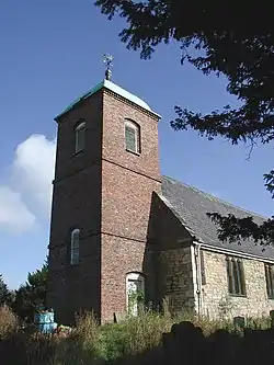A stone church with a prominent brick tower, capped with a cupola