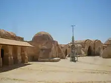 Rocky buildings and an antenna-like structure in a desert.