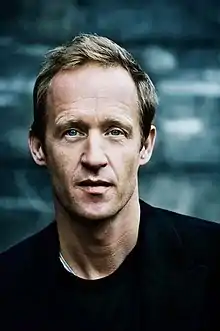 white male wearing black t-shirt, looking directly at camera